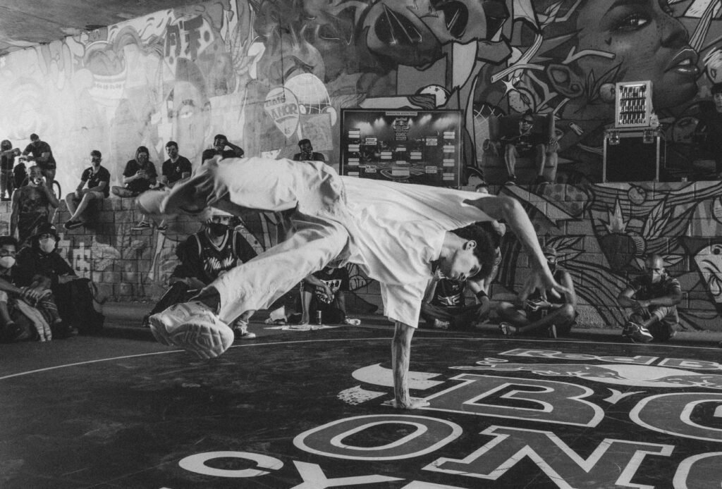 Joven realizando acrobacias de breakdance con otros jovenes observando